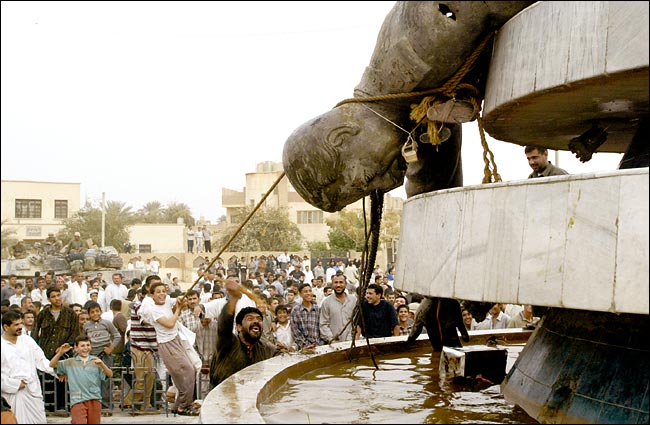 Iraqi citizens pull down a statue of Saddam Hussein with the help of U.S. soldiers from Second Battalion, Karbala, April 6, 2003.